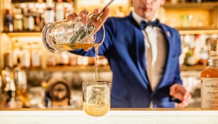 Federico Pavan pouring cocktail in a glass